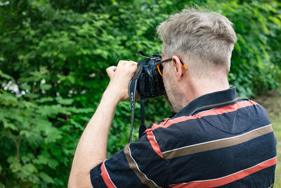 Rear view of man photographing outdoors