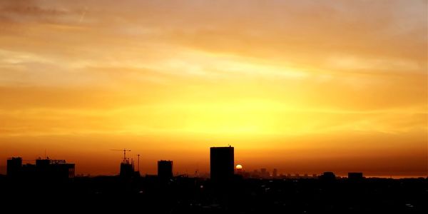 Silhouette buildings against sky during sunset