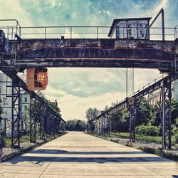 Footbridge over railroad tracks against sky