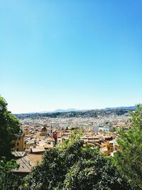 High angle view of houses in town against clear blue sky