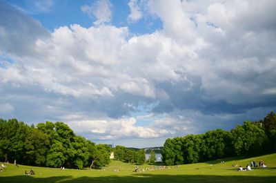 Trees on landscape against cloudy sky