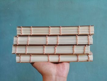Cropped image of hand holding book against white background