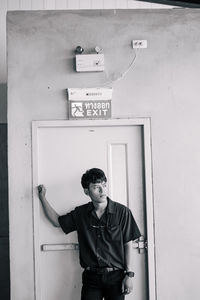 Portrait of young man standing against door