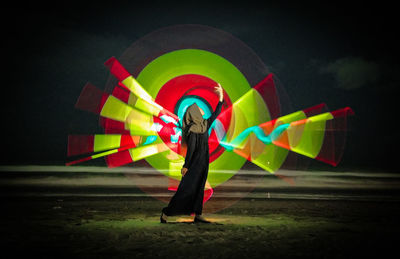 Full length rear view of man holding umbrella standing at night