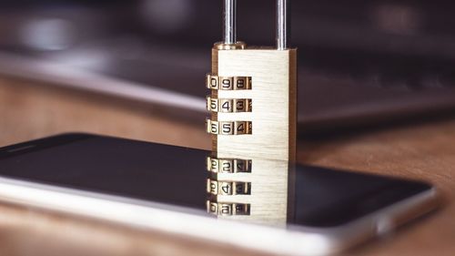 Close-up of padlock and smart phone