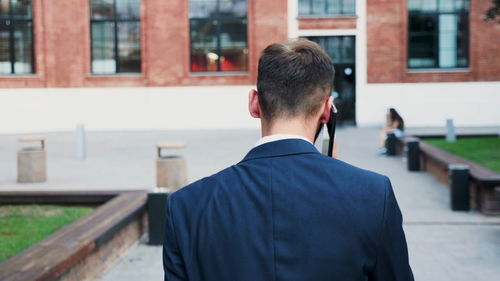 Rear view of man standing against buildings in city