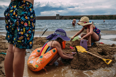 Low level photo of young children digging in sand at beach