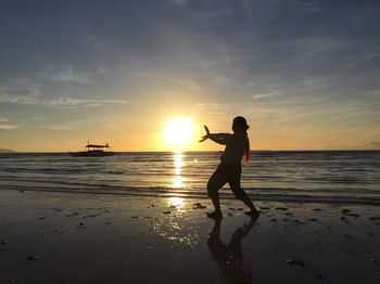 Optical illusion of man holding sun at beach during sunset