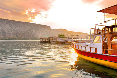 Boats moored in river against sky during sunset