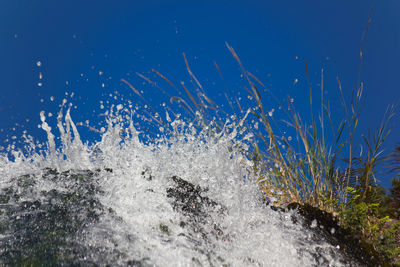 Water splashing in sea against clear blue sky