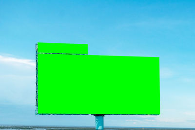 Green arrow sign against blue sky