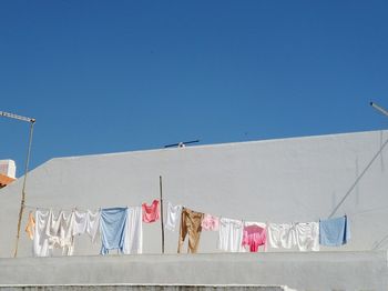 Low angle view of clothes drying on clothesline against clear blue sky