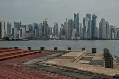 Modern buildings by river against sky in city