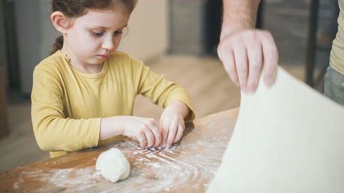 Midsection of baby girl on table in kitchen