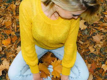 High angle view of woman with yellow leaves during autumn