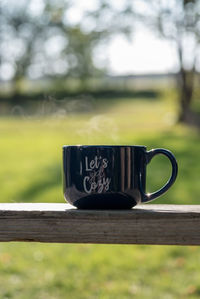 Close-up of coffee cup with text on table at backyard