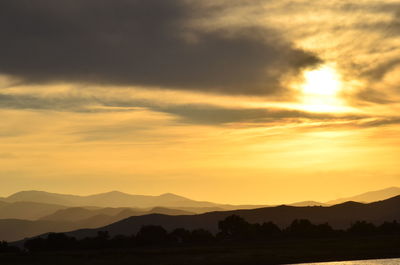 Scenic view of silhouette mountains against orange sky