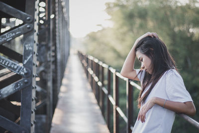 Side view of woman standing on bridge