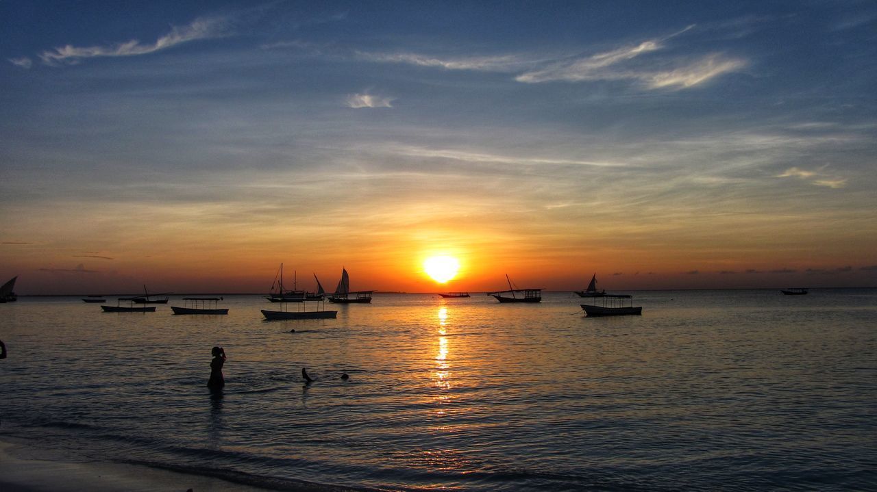 BOATS MOORED IN SEA AGAINST SKY DURING SUNSET