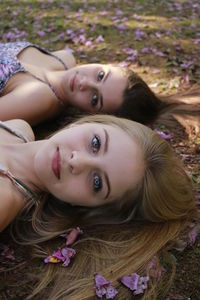 Close-up portrait of smiling female fiends lying on field