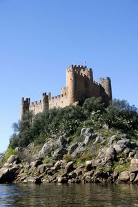 Castle on rock against clear blue sky