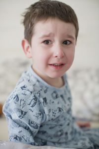 Crying boy wearing pajamas on bed