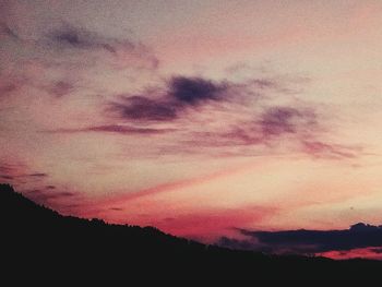 Low angle view of silhouette trees against dramatic sky