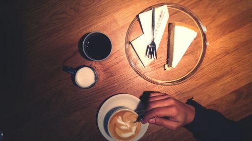 Cropped image of person having coffee and cake on table