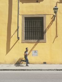 Full length of man running on sidewalk by building