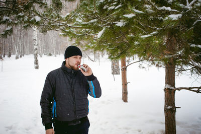 Man smoking electronic cigarette on snow covered field