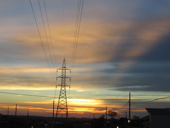 Low angle view of silhouette electricity pylon against sky during sunset