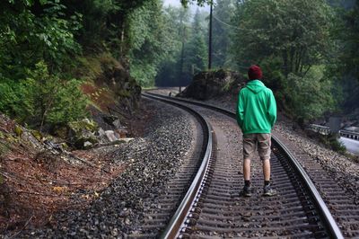 Rear view of man standing on railroad track