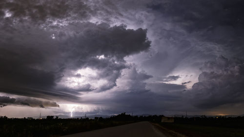 Road passing through landscape against cloudy sky