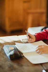 Midsection of woman reading book on table