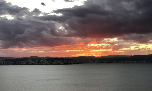 Scenic view of sea against dramatic sky during sunset