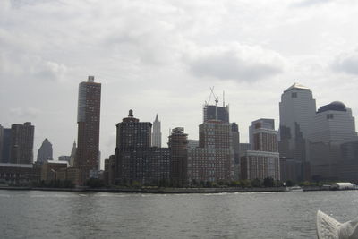 Buildings by river against sky in city