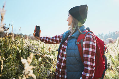 Young woman taking selfie with smartphone during vacation trip in mountains. spending vacations