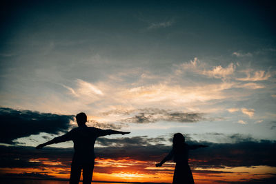 Silhouette people standing against sky during sunset