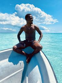Shirtless man swimming in sea against sky