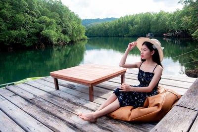 Woman sitting on wood against lake