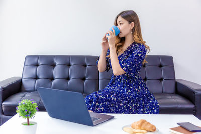 Young woman using mobile phone while sitting on sofa