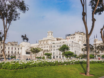 Statue in city against sky