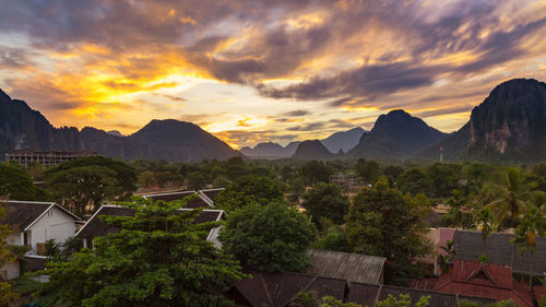 Scenic view of buildings and mountains against sky during sunset