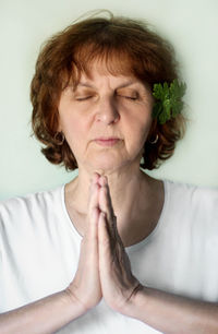 Close-up of woman with eyes closed meditating against white background