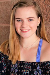 Portrait of smiling teenage girl standing against wall