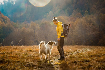 Full length of woman standing with dog on field