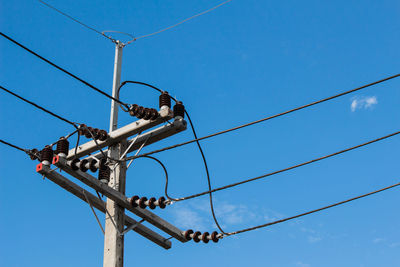 Low angle view of telephone pole against blue sky