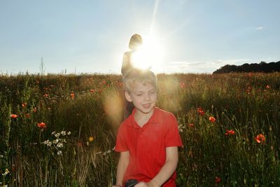 Boy standing on field against sky