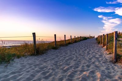 Wooden posts at beach against sky during sunset