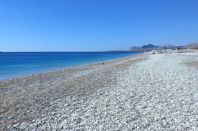 Scenic view of beach against clear blue sky